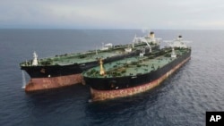 In this undated photo released July 11, 2023, by the Indonesian Maritime Security Agency, Iranian-flagged tanker MT Arman 114, right, and Cameroon-flagged tanker, MT S Tinos, are seen after they are caught conducting illegal oil transfers.