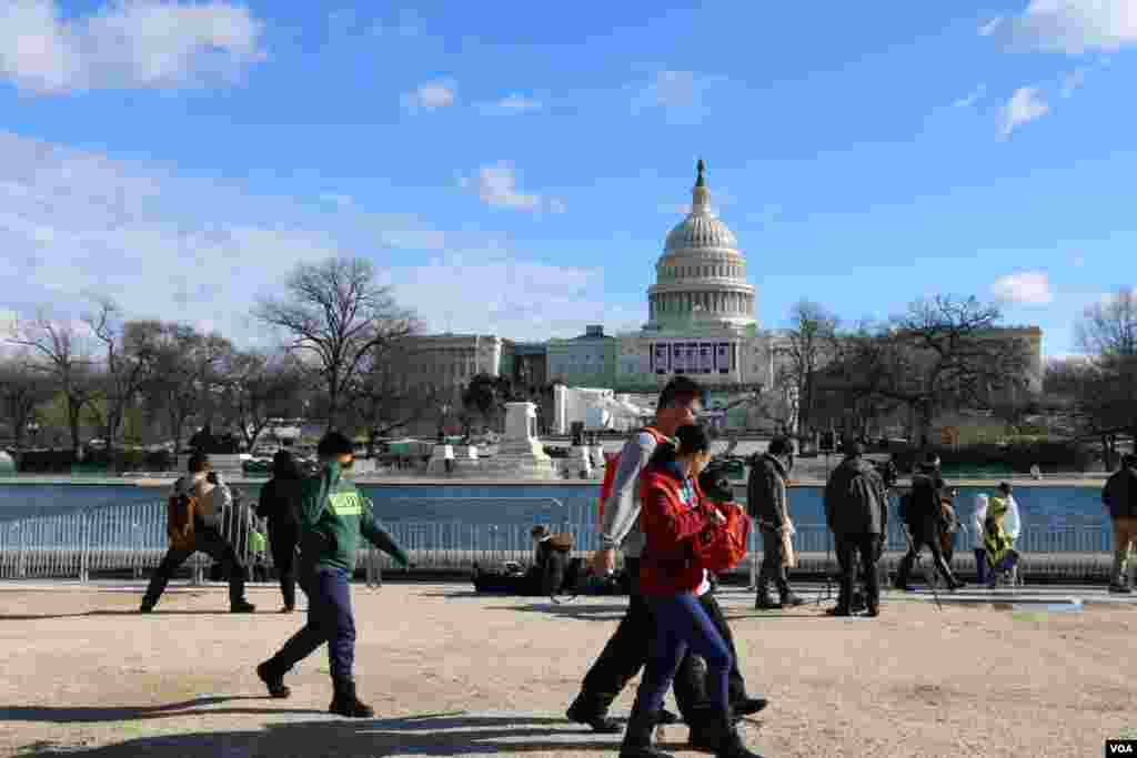 گردشگران در مقابل استخر جلوی کنگره، دو روز پیش از مراسم تحلیف، عکس یادگاری می گیرند.
