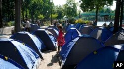 A volunteer from Doctors Without Borders takes notes on migrants who set up tents along a canal in Paris, May 27, 2020. 