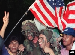 U.S. soldiers carry an American flag through the streets of Panama City as they celebrate with Panamanian citizens in Jan. 1990 following the surrender of Panamanian leader Manuel Noriega.