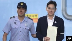 Miliuner pewaris Samsung, Lee Jae-yong (kanan), meninggalkan gedung pengadilan di Seoul dengan diborgol dan dikawal polisi akhir Agustus lalu (foto: dok). 