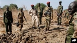 Southern army officers in Northern Bahr el Ghazal state in Sudan, peer into a bomb crater created from one of the bombs dropped by the northern Sudanese army on a southern army base in the disputed border zone of Kiir Adem, where Southern Sudan meets Darf