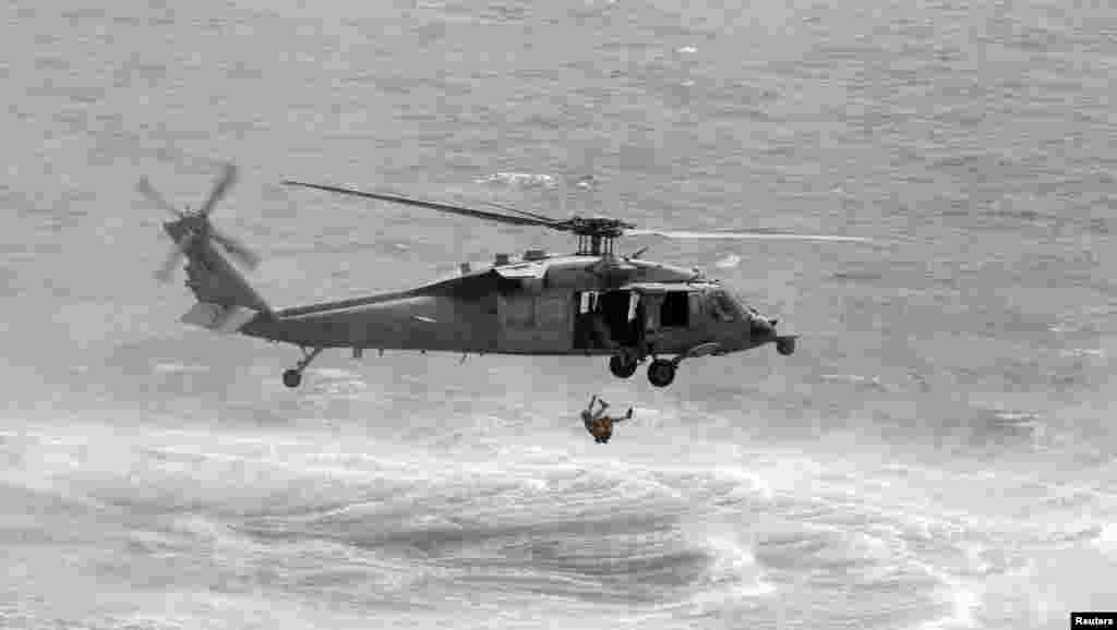 A U.S. Navy diver cuts himself free after getting entangled with his safety device as he jumps from a USS Navy helicopter to perform a mine-sweeping exercise during the International Mine Countermeasures Exercise (IMCMEX) in the Middle East Gulf.