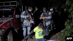 Un presunto pandillero permanece arrodillado mientras es detenido por agentes de la sección táctica operativa (STO) de la Policía Nacional Civil el 29 de octubre de 2020 en la madrugada, en San Marcos, El Salvador.