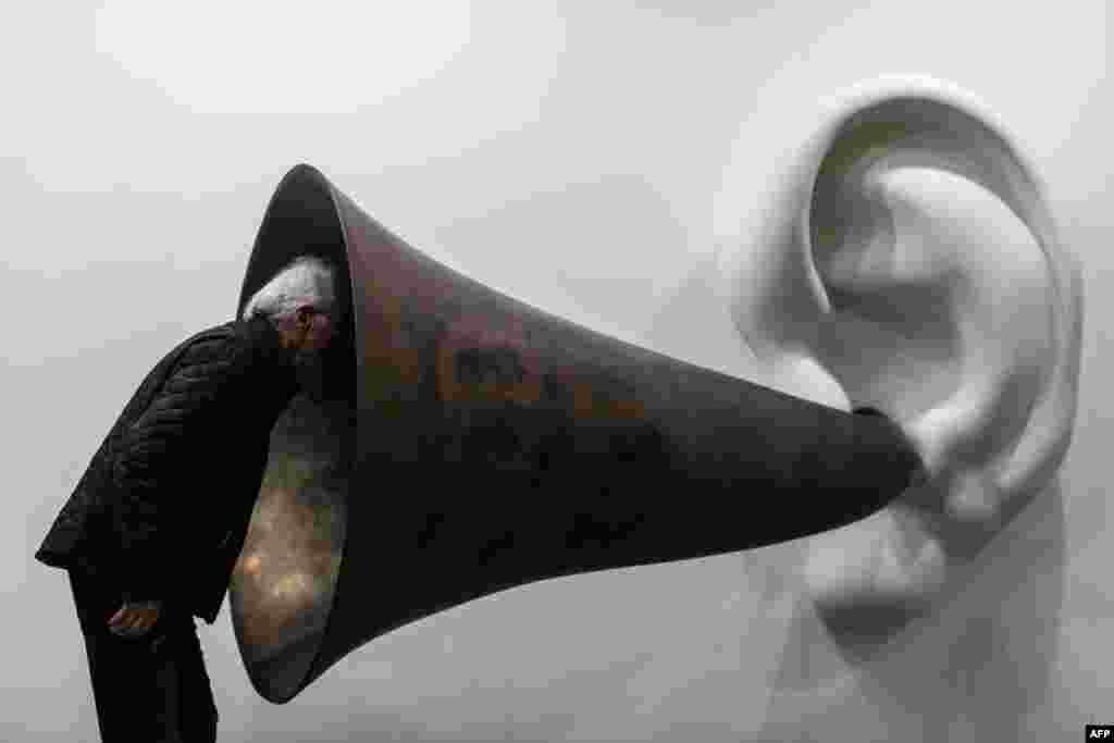 Seorang pengunjung mengintip ke karya seniman AS John Baldessari, &quot;Beethoven&#39;s Trumpet (With Ear) Opus # 133&quot; di pameran Art Basel di Hong Kong.