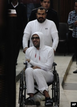 FILE - Mohammed Soltan is pushed by his father, Salah, during a court appearance in Cairo, Egypt, March 9, 2015.