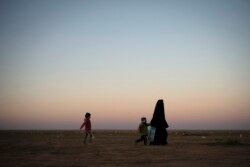 Seorang wanita berjalan bersama anak-anaknya di area penyaringan Pasukan Demokratik Suriah (SDF) yang didukung AS di luar Baghuz, Suriah, 1 Maret 2019. (Foto: AP/Felipe Dana)