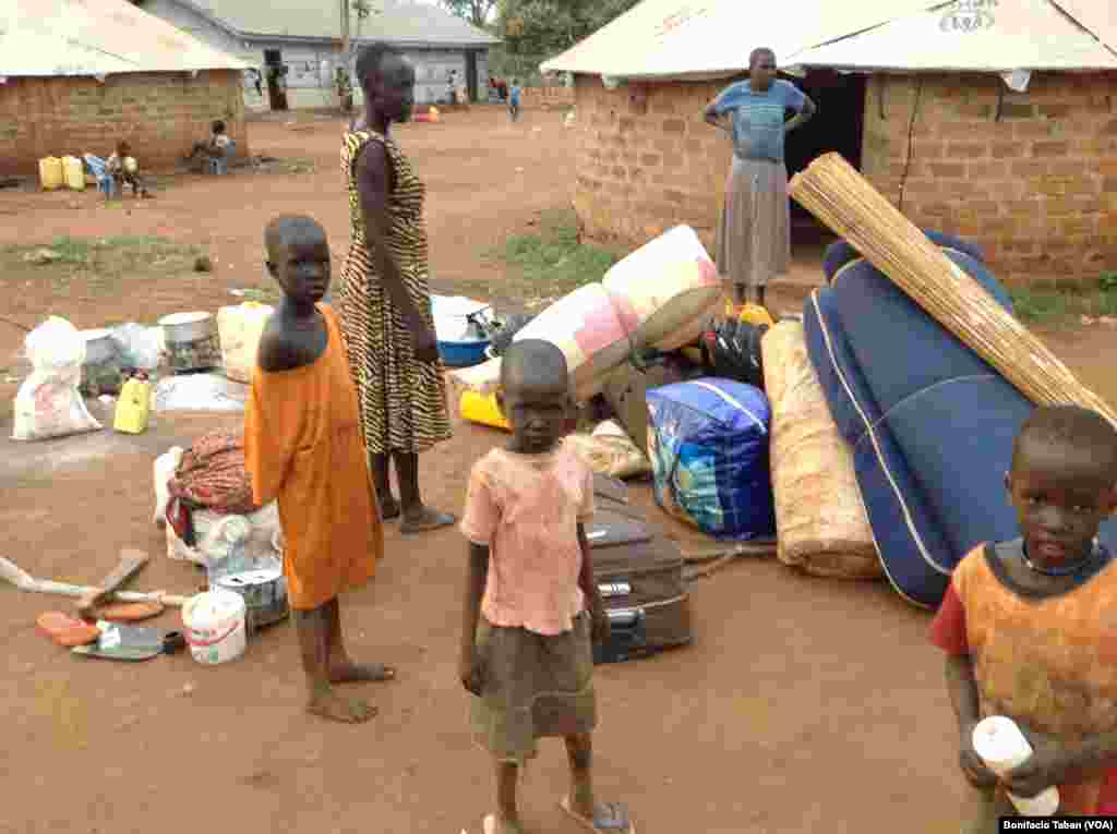 New arrivals from South Sudan stand next to their few possessions -- a jerry can, mattresses, suitcases, a machete and a pair of flip-flops -- in Kiryandongo settlement in northern Uganda. 