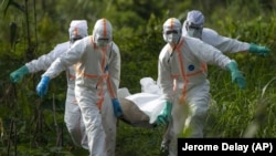 Des agents d'inhumation vêtus de tenues de protection portent les restes d'une victime du virus Ebola, à Beni, en RDC, le dimanche 14 juillet 2019.