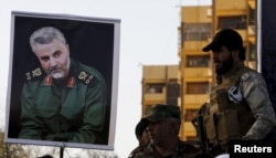 FILE - Members of the mainly Shi'ite Hashid Shaabi militia hold a portrait of Quds Force Commander Qassem Suleimani during a demonstration to show support for Yemen's Shi'ite Houthis and in protest of an air campaign in Yemen by a Saudi-led coalition, in Baghdad, March 31, 2015.