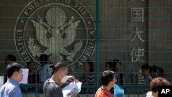 FILE - In this July 26, 2018, photo, visa applicants wait to enter the U.S. Embassy in Beijing, China. The U.S. Homeland Security Department says more than 700,000 foreigners who were supposed to leave the country during a recent 12-month period overstayed their visas.