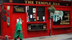 Seorang pria berpakaian kostum St Patrick berjalan melewati Bar Temple di pusat Kota Dublin, 16 Maret 2020. Seluruh bar di Dublin tutup untuk mencegah penyebaran pandemi virus corona. (Foto: AP)