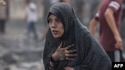 FILE - A Palestinian woman covered in dust, reacts following an Israeli airstrike on buildings in Rafah, in the southern Gaza Strip on October 17, 2023, amid the ongoing battles between Israel and the Palestinian group Hamas.