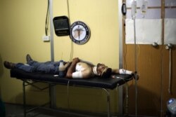 FILE - A wounded man is treated at a medical center of the Syrian American Medical Society (SAMS) following reported airstrikes, in the town of Kfar Batna, Syria, June 11, 2016.