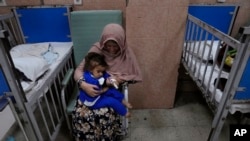 An Afghan woman holds her sick granddaughter, where she undergoes treatment in the malnutrition part of the Indira Gandhi Children's Hospital in Kabul, Afghanistan on February 24, 2022. (AP Photo/Hussein Malla)