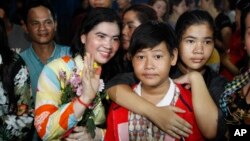 A prominent leader of Cambodia's land rights activist Tep Vanny, second from left, gestures upon the arrival at her home in Boeung Kak, in Phnom Penh, Cambodia, Monday, Aug. 20, 2018. A prominent leader of Cambodia's land rights movement and three women activists who were sent to prison with her were freed Monday under a royal pardon. (AP Photo/Heng Sinith)