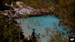 FILE - People relax and swim in Mallorca, Spain, June 16, 2020. Two British tourists hiking on the island were apparently swept away in a flash found on Sept. 3, 2024. One body was found, and emergency workers continue to search for the other person.