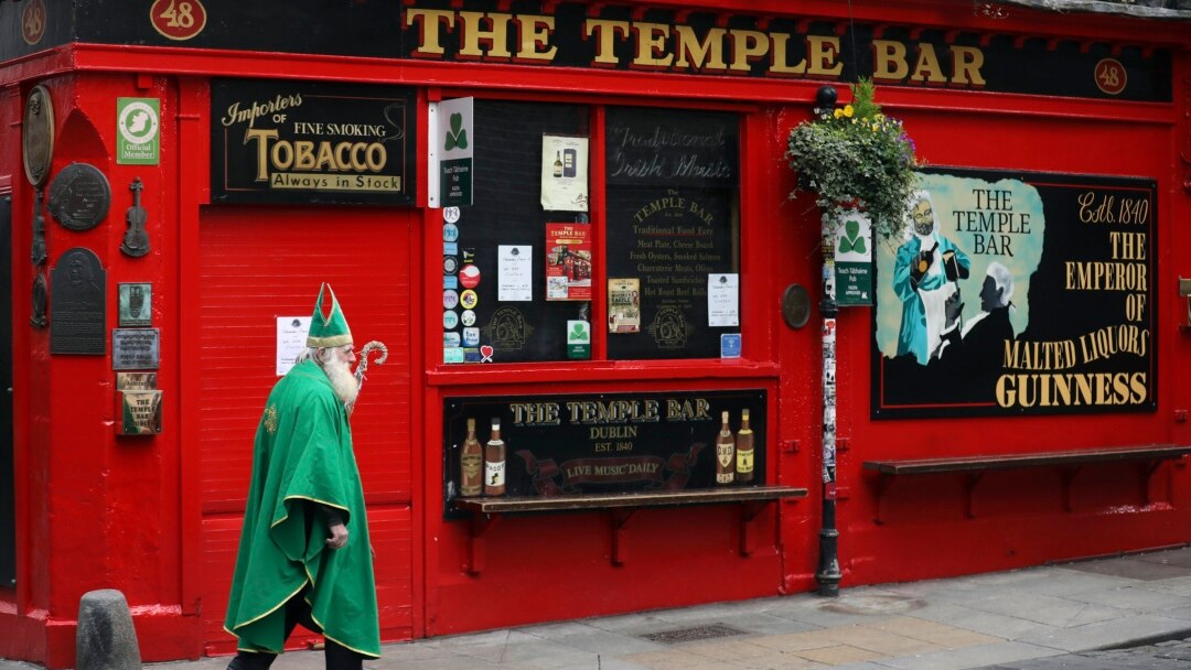 Seorang pria berpakaian kostum St Patrick berjalan melewati Bar Temple di pusat Kota Dublin, 16 Maret 2020. Seluruh bar di Dublin tutup untuk mencegah penyebaran pandemi virus corona. (Foto: AP)
