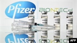 Sebuah gambar ilustrasi menunjukkan botol dengan stiker Vaksin Covid-19 terpasang dan jarum suntik dengan logo perusahaan farmasi AS Pfizer dan mitra Jerman BioNTech, pada 17 November 2020. (Foto: AFP/Justin Tallis)