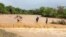 FILE — People are helped to cross a flooded Muuoni River, Makueni county, Nov. 24, 2023. 