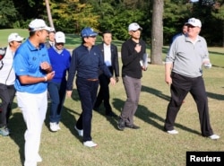 FILE - U.S. President Donald Trump, right, talks with Japan's Shinzo Abe as Japanese professional golfer Hideki Matsuyama looks on, as they play golf at the Kasumigaseki Country Club in Kawagoe, in this photo released by Japan's Cabinet Public Relations Office.