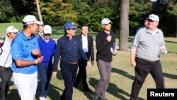 Presiden Donald Trump (Kanan) berbincang dengan Perdana Menteri Jepang Shinzo Abe (empat dari kanan), didampingi pegolf profesional Jepang, Hideki Matsuyama, pada saat bermain golf di Kasumigaseki Country Club di Kawagoe, dalam foto yang dirilis Kantor Humas Kabinet Jepang, via Kyodo, 5 November 2017. (Foto: Humas Kabinet Jepang via Kyodo, via Reuters)