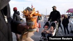 People try to keep a social distance due to the coronavirus disease (COVID-19) pandemic as they wait in line for French fries at a stand on the boardwalk in Rehobeth Beach, Delaware, Jan. 2, 2021.