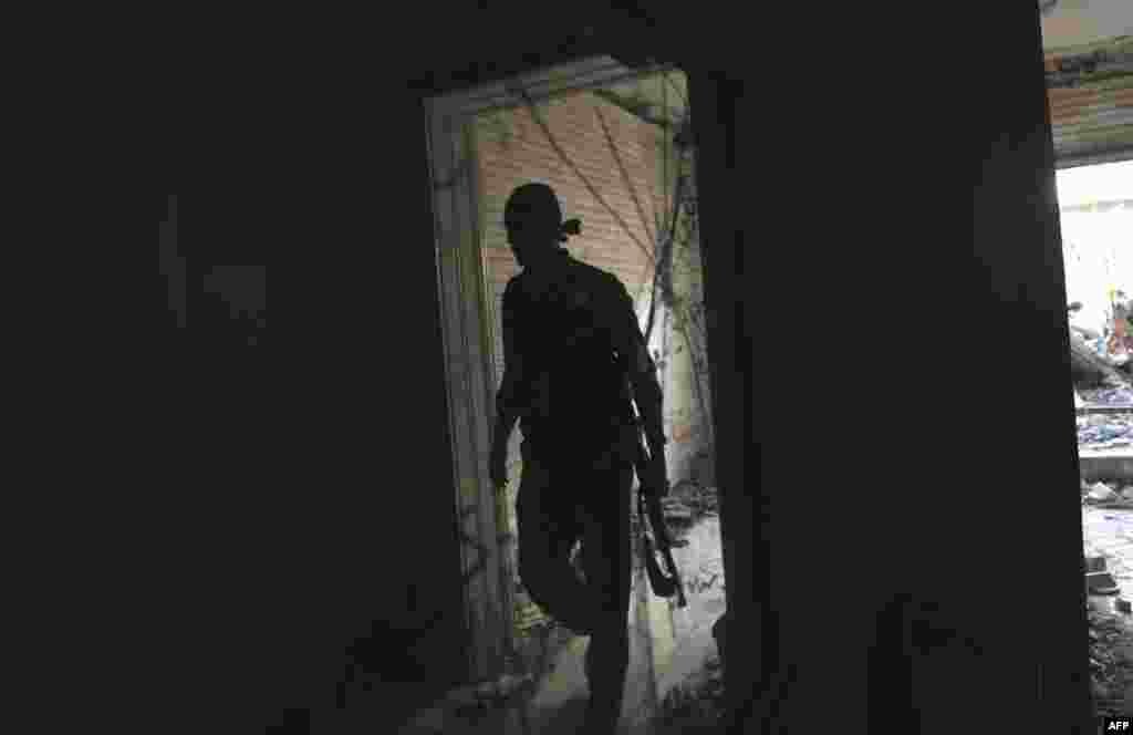 A Syrian opposition fighter walks into a building during clashes with the Syrian army in Aleppo, March 27, 2013.