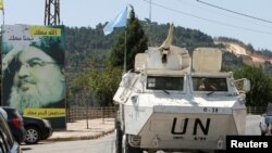 A U.N. peacekeepers vehicle drives past a poster depicting Lebanon's Hezbollah leader Sayyed Hassan Nasrallah in Adaisseh village, near the Lebanese-Israeli border, southern Lebanon, August 6, 2021.