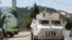 A U.N. peacekeepers vehicle drives past a poster depicting Lebanon's Hezbollah leader Sayyed Hassan Nasrallah in Adaisseh village, near the Lebanese-Israeli border, southern Lebanon, August 6, 2021.