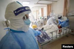 Medical workers in protective suits attend to a patient inside an isolated ward of Wuhan Red Cross Hospital in Wuhan, the epicenter of the novel coronavirus outbreak, in Hubei province, China, Feb. 16, 2020.