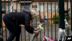 一名婦女在法國卡爾卡松的警察總署大門前獻花悼念為救人質犧牲的警官貝爾特拉姆。（2018年3月24日）