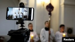 Ilustrasi.Sebuah ponsel digunakan untuk mengirimkan prosesi Jumat Agung secara online, karena wabah virus corona di Polandia, di gereja Katolik di Gora Kalwaria, Polandia,10 April 2020. (Foto: Reuters/Kacper Pempel)