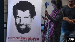 A journalist stands in front of a poster featuring jailed businessman and philanthropist Osman Kavala during a press conference held by his lawyers, Oct. 31, 2018.