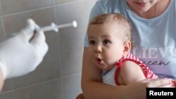 Дитина в одній із лікарень Києва реагує на вакцинацію. Фото: Reuters/Valentyn Ogirenko