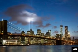 In this Sept. 10, 2014 file photo, the Tribute in Light rises behind the Brooklyn Bridge and buildings adjacent to the World Trade Center complex in New York.