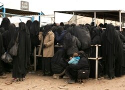 FILE - Women line up for aid supplies at the al-Hol camp in Hassakeh province, Syria, March 31, 2019.