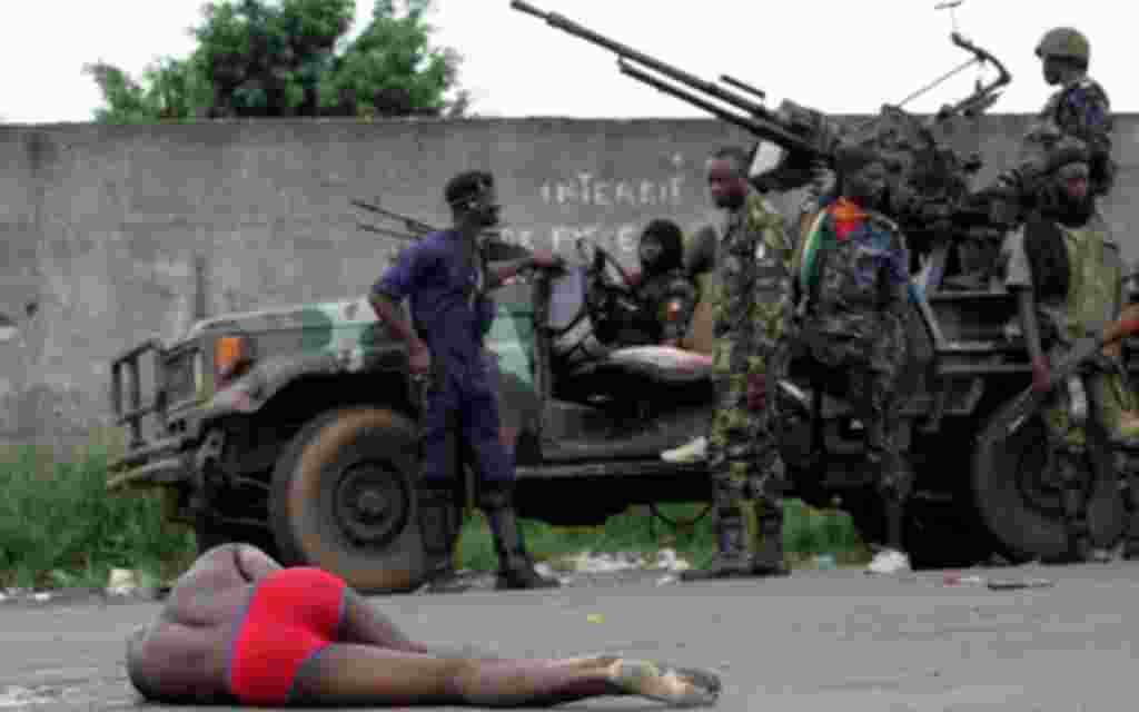 Forces loyal to Ivorian presidential claimant Alassane Ouattara wait behind an injured man in the capital Abidjan, April 2, 2011. Soldiers of Ivory Coast's rival leaders battled for the presidential palace, military bases and state TV in the main city Abi