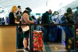 FILE - Travelers wear face masks while waiting to check in at the Southwest Airlines counter in Denver International Airport, Dec. 22, 2020, in Denver.