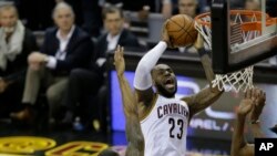 La superstar de Cleveland LeBron James, numéro 23 de Cleveland Cavaliers, marque un panier malgré un contre d’Andre Igougala, le 9 de Golden State Warriors, lors d’un match de finale de la NBA à Cleveland, 9 juin 2017.