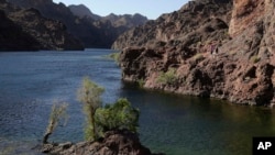 FILE - Hikers make their way along the banks of the Colorado River near Willow Beach, Arizona, April 14, 2013. 