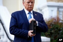 FILE - President Donald Trump holds a Bible as he visits outside St. John's Church across Lafayette Park from the White House, June 1, 2020.
