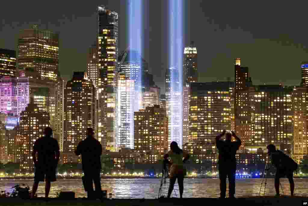 People look at the September 11 tribute lights in New York City across from the Hudson River from Jersey City, New Jersey, Sept. 11, 2019, on the 18th anniversary of the attacks on the Twin Towers of the World Trade Center.
