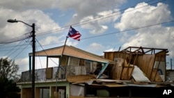 A political party banner waves over a home damaged in the passing of Hurricane Maria, in the community of Ingenio in Toa Baja, Puerto Rico, Oct. 2, 2017. President Donald Trump is planning to visit the U.S. territory on Tuesday.