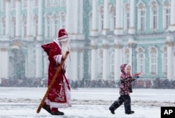 A man wearing a Ded Moroz, or Grandfather Frost, costume walks in snowfall at Dvortsovaya Square in St. Petersburg, Russia, Saturday, Jan. 3, 2015.