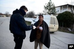 Greek authorities detain a migrant after he entered Greece from Turkey, in the village of Thourio, Evros region near the Greek-Turkish border, March 9, 2020.
