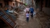 Una niña camina con su madre y su abuela por una calle con muebles amontonados y basura a los lados, en una zona afectada por las inundaciones en Paiporta, Valencia, España, el martes 5 de noviembre de 2024. 