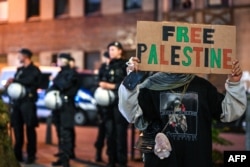 FILE - A pro-Palestine demonstrator holds up a placard in front of police officers during a "in solidarity with Gaza" rally in Duisburg, western Germany, on October 9, 2023.