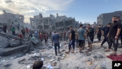 In this frame grab from video, Palestinians stand and others search for survivors and bodies following Israeli airstrikes at the Jabaliya refugee camp on Gaza City’s outskirts, Oct. 31.