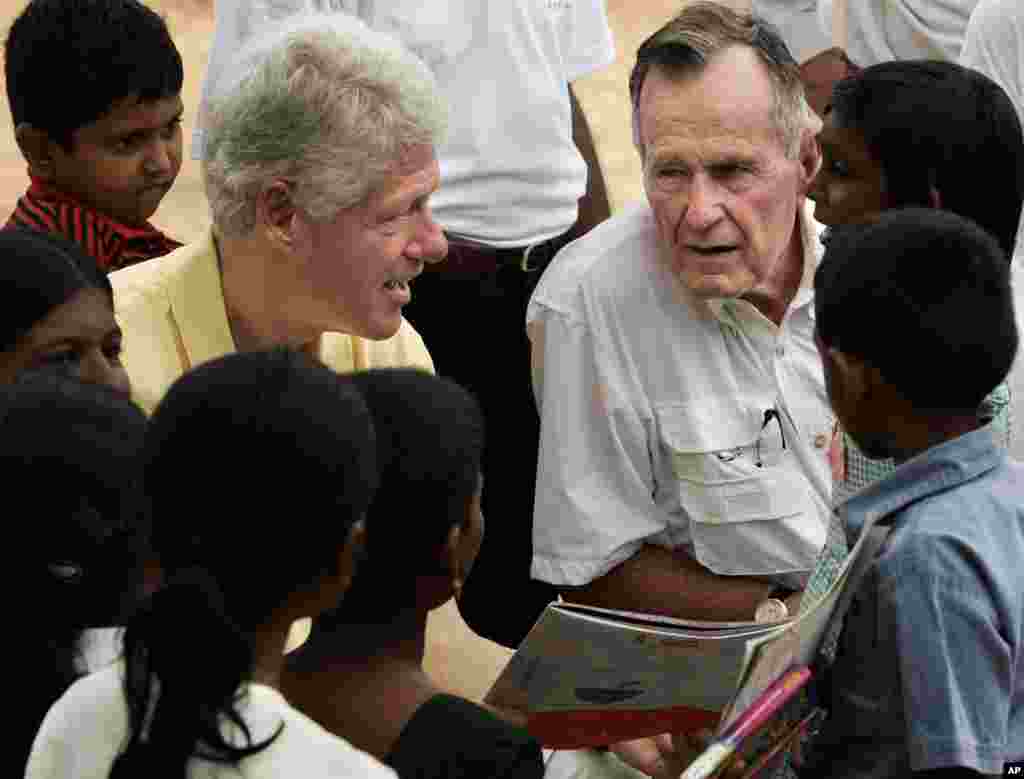 Former U.S. presidents Bill Clinton and George H.W. Bush talk with children as they visit displaced residents from the December tsunami in Weligama, Sri Lanka, Monday, Feb. 21, 2005.